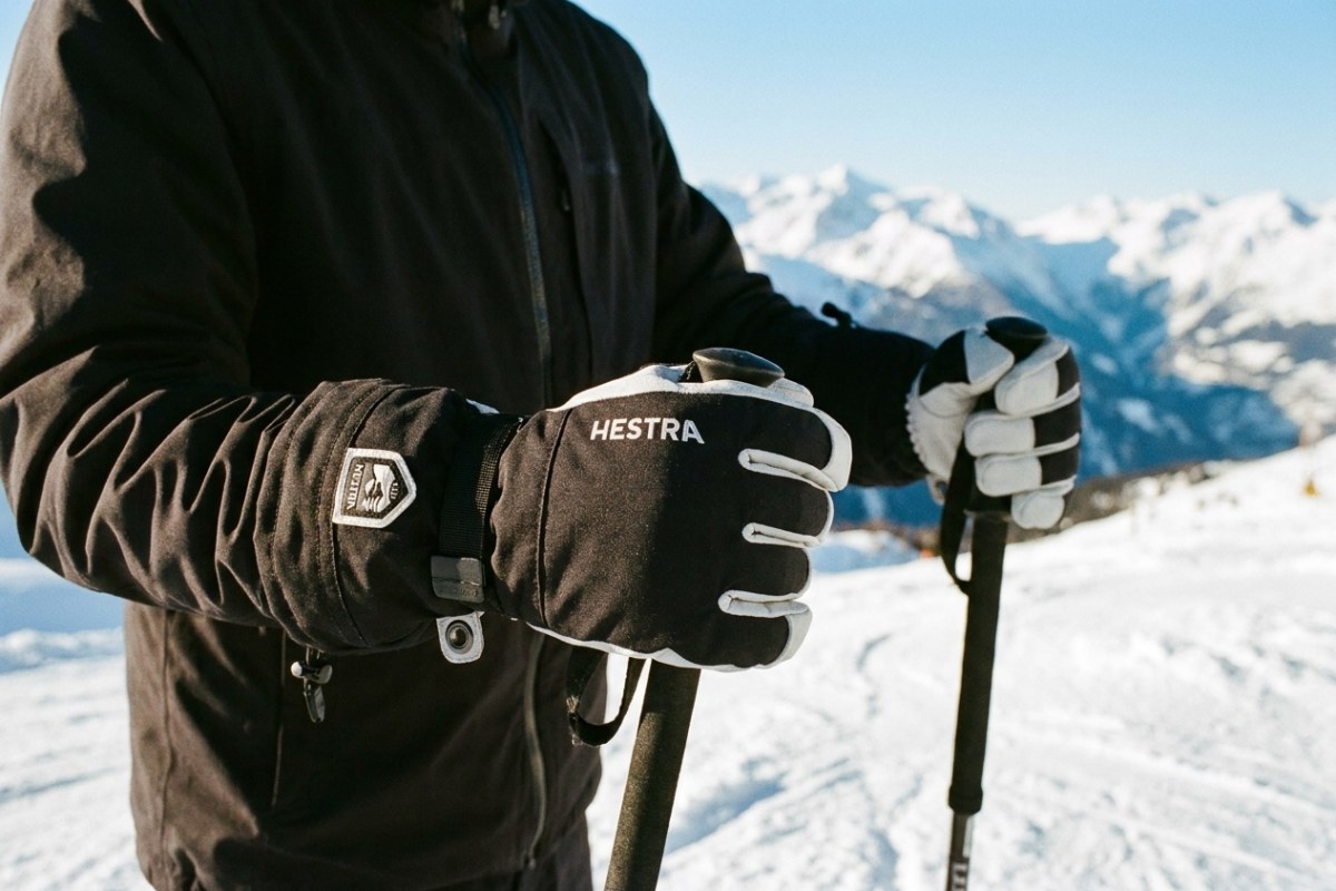 Army Leather Heli Ski handschoenen op de piste Wintersporter met Hestra Army Leather Heli Ski handschoenen en skistokken in besneeuwde bergen.